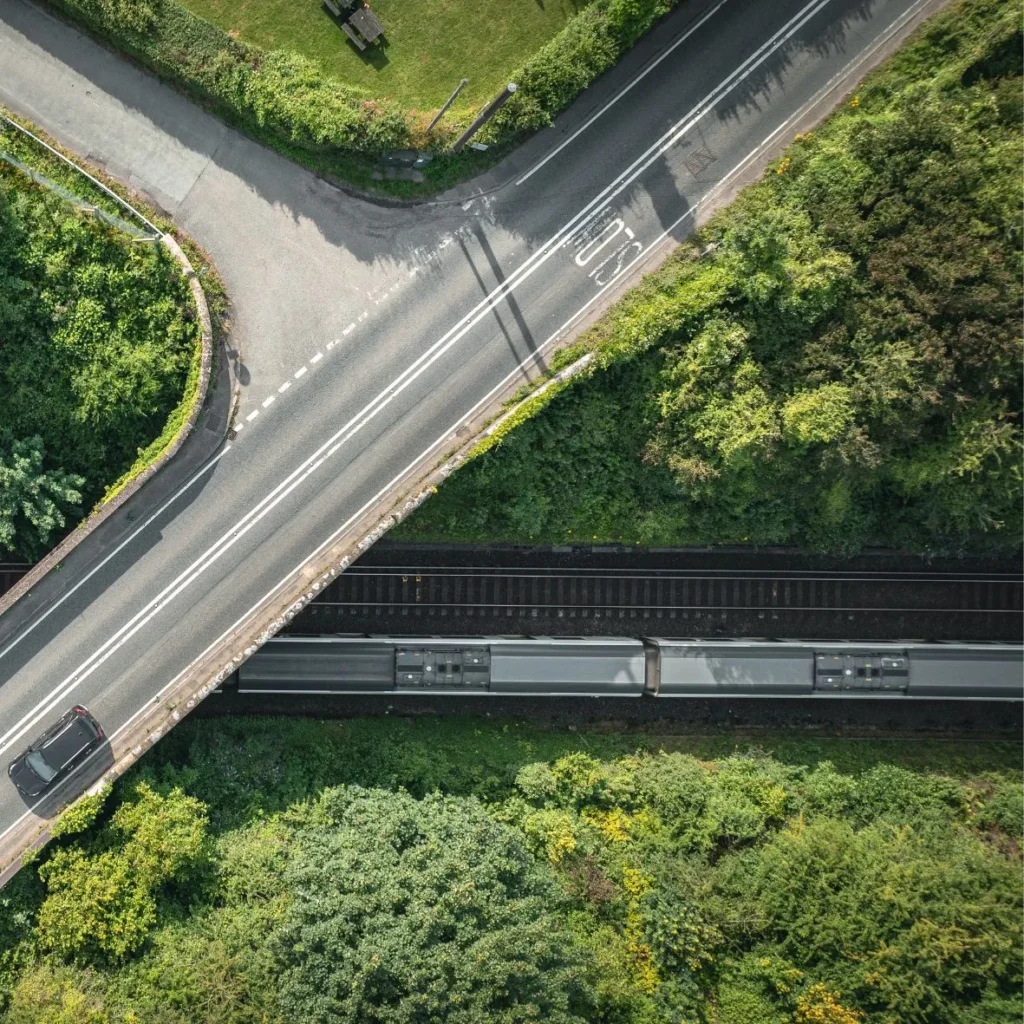 Road and railway line surrounded by trees.